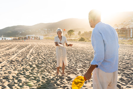 Beautiful happy senior couple dating at the seaside during summertime - Mature married couple in love bonding outdoors at the beach, concepts about elderly lifestyle, relationship and quality of lifeの写真素材