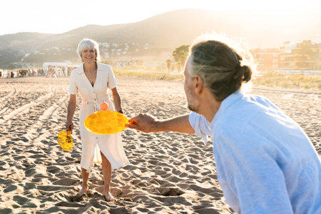 Beautiful happy senior couple at the seaside during summertime - Mature married couple in love bonding outdoors at the beach, concepts about elderly lifestyle, relationship and quality of lifeの写真素材