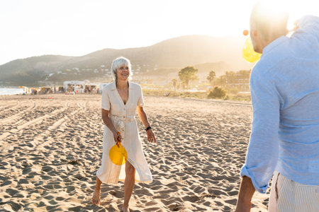 Beautiful happy senior couple dating at the seaside during summertime - Mature married couple in love bonding outdoors at the beach, concepts about elderly lifestyle, relationship and quality of lifeの写真素材