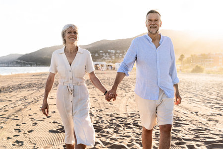 Beautiful happy senior couple at the seaside during summertime - Mature married couple in love bonding outdoors at the beach, concepts about elderly lifestyle, relationship and quality of lifeの写真素材