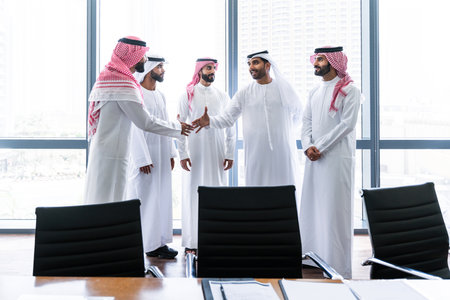 Arab businessmen wearing emirati and saudi kandura meeting in office for business deal - Corporate business group of middle-eastern people working in an international company in middle eastの写真素材