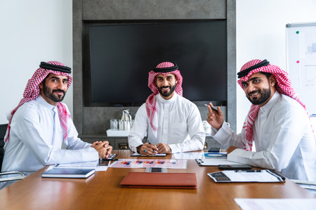 Arab businessmen wearing saudi kandura meeting in office for business deal - Corporate business group of middle-eastern people working in an international company in middle eastの写真素材