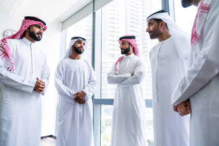Arab businessmen wearing emirati and saudi kandura meeting in office for business deal - Corporate business group of middle-eastern people working in an international company in middle eastの写真素材