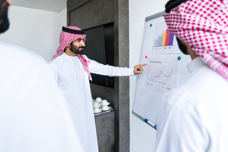 Arab businessmen wearing saudi kandura meeting in office for business deal - Corporate business group of middle-eastern people working in an international companyの写真素材