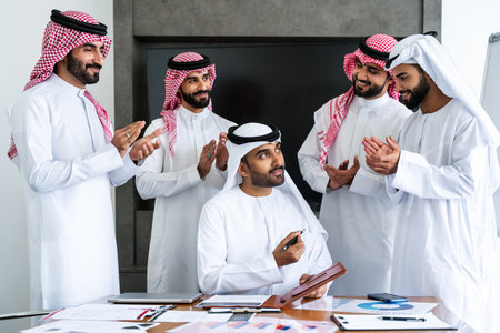 Arab businessmen wearing emirati and saudi kandura meeting in office for business deal - Corporate business group of middle-eastern people working in an international companyの写真素材