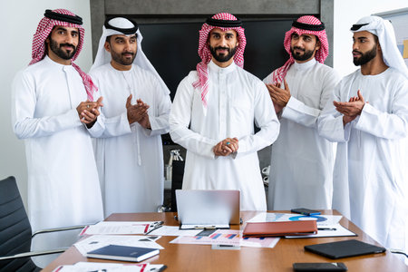 Arab businessmen wearing emirati and saudi kandura meeting in office for business deal - Corporate business group of middle-eastern people working in an international company in middle eastの写真素材