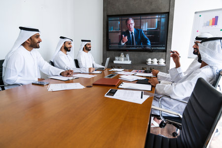 Arab businessmen wearing emirati kandura meeting in office for business deal - Corporate business group of middle-eastern people working in an international company in middle eastの写真素材