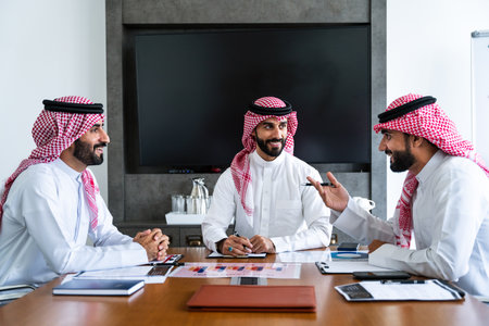 Arab businessmen wearing saudi kandura meeting in office for business deal - Corporate business group of middle-eastern people working in an international company in middle eastの写真素材