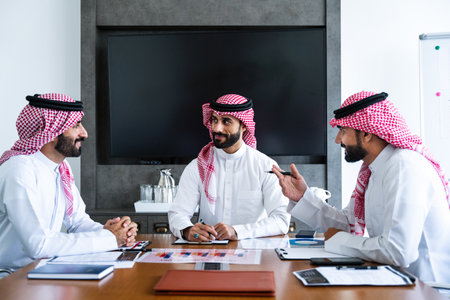 Arab businessmen wearing saudi kandura meeting in office for business deal - Corporate business group of middle-eastern people working in an international company in middle eastの写真素材