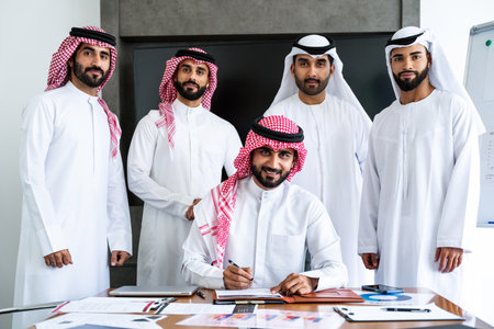 Arab businessmen wearing emirati and saudi kandura meeting in office for business deal - Corporate business group of middle-eastern people working in an international company in middle eastの写真素材