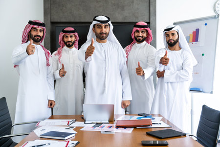 Arab businessmen wearing emirati and saudi kandura meeting in office for business deal - Corporate business group of middle-eastern people working in an international company in middle eastの写真素材