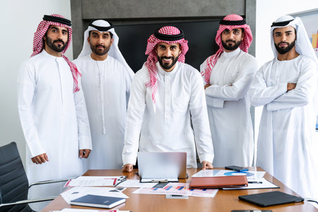 Arab businessmen wearing emirati and saudi kandura meeting in office for business deal - Corporate business group of middle-eastern people working in an international company in middle eastの写真素材