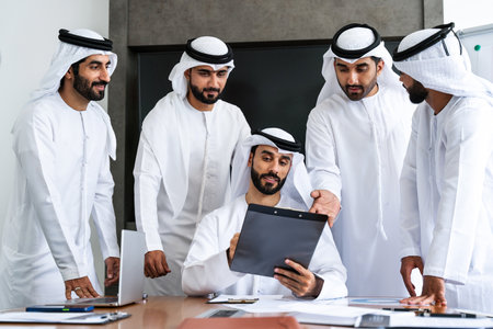 Arab businessmen wearing emirati kandura meeting in office for business deal - Corporate business group of middle-eastern people working in an international company in middle eastの写真素材