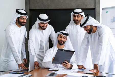Arab businessmen wearing emirati kandura meeting in office for business deal - Corporate business group of middle-eastern people working in an international company in middle eastの写真素材