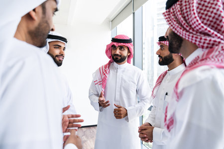 Arab businessmen wearing emirati and saudi kandura meeting in office for business deal - Corporate business group of middle-eastern people working in an international company in middle eastの写真素材