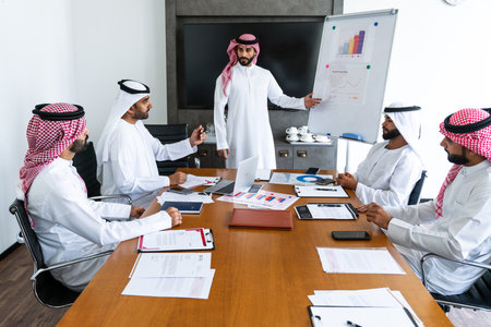 Arab businessmen wearing emirati and saudi kandura meeting in office for business deal - Corporate business group of middle-eastern people working in an international company in middle eastの写真素材