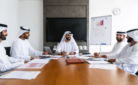 Arab businessmen wearing emirati kandura meeting in office for business deal - Corporate business group of middle-eastern people working in an international company in middle eastの写真素材