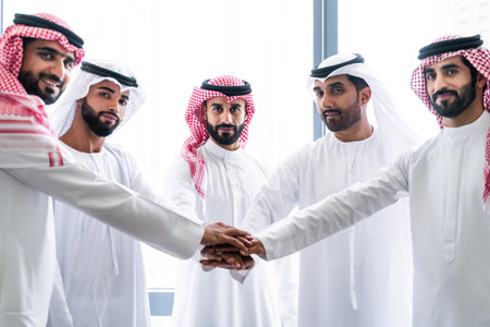 Arab businessmen wearing emirati and saudi kandura meeting in office for business deal - Corporate business group of middle-eastern people working in an international company in middle eastの写真素材