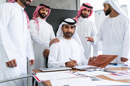 Arab businessmen wearing emirati and saudi kandura meeting in office for business deal - Corporate business group of middle-eastern people working in an international company in middle eastの写真素材