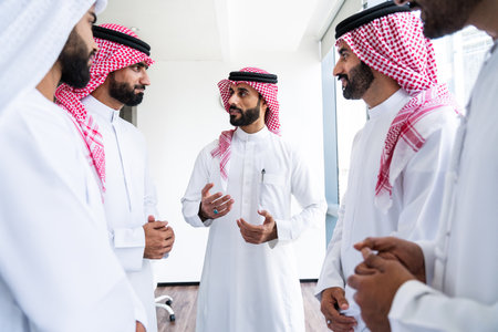 Arab businessmen wearing emirati and saudi kandura meeting in office for business deal - Corporate business group of middle-eastern people working in an international company in middle eastの写真素材