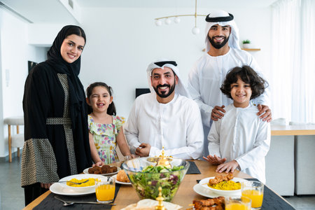Happy arab family wearing emirati clothing spending time together at home during dinner after...