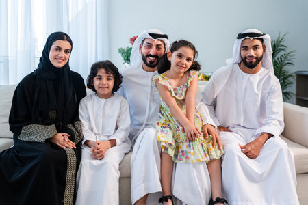 Happy arab family wearing emirati clothing spending time together at home - Middle-eastern parents and children bonding in modern apartment in Dubaiの写真素材
