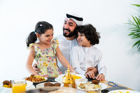 Happy arab family wearing emirati clothing spending time together at home during dinner after ramadan - Middle-eastern parents and children bonding in modern apartment in Dubaiの写真素材