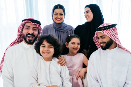 Happy arab family wearing saudi arabia clothing spending time together at home during dinner - Middle-eastern saudi parents and children celebrating ramadan after day fastingの写真素材