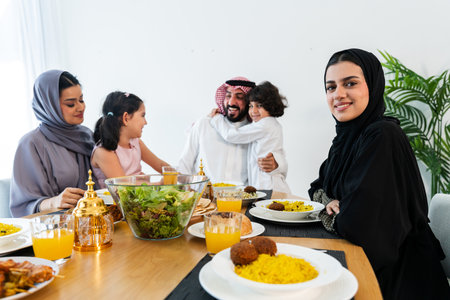 Happy arab family wearing saudi arabia clothing spending time together at home during dinner - Middle-eastern saudi parents and children celebrating ramadan after day fastingの写真素材