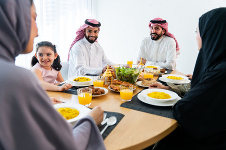 Happy arab family wearing saudi arabia clothing spending time together at home during dinner - Middle-eastern saudi parents and children celebrating ramadan after day fastingの写真素材