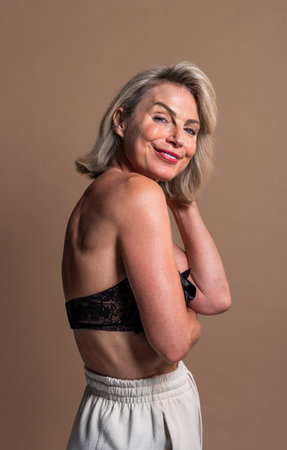Beauty portrait of beautiful mature woman, concepts about cosmetics, skincare and wellness. Mature woman smiling and touching her hairの写真素材