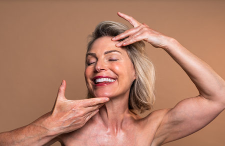 Beauty portrait of beautiful mature woman, concepts about cosmetics, skincare and wellness. Experienced beautician gently massaging face of relaxed mature woman during professional skincare treatmentの写真素材