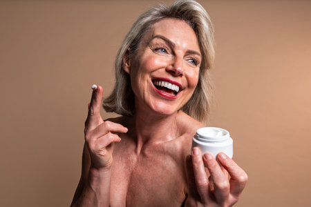 Beauty portrait of beautiful mature woman, concepts about cosmetics, skincare and wellness. Happy mature woman holding a jar of moisturizing creamの写真素材