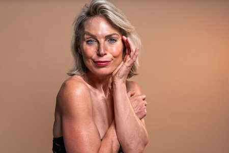 Beauty portrait of beautiful mature woman, concepts about cosmetics, skincare and wellness. Portrait of a beautiful. Smiling mature woman gently touching her faceの写真素材