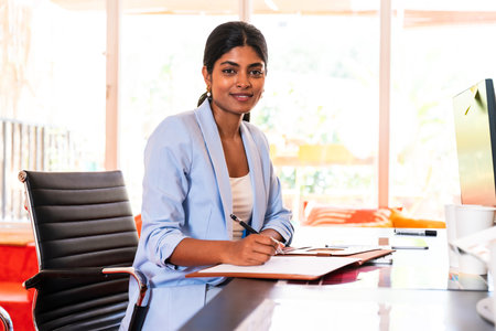 Beautiful indian business woman working in a coworking corporate company office - Young female wearing business casual clothing works in a creative startup tech company, concepts about business and daily office lifestyleの写真素材
