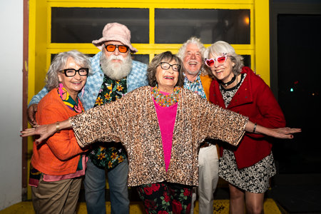 Group of happy senior friends with fancy clothing having party in the night on city streets -...