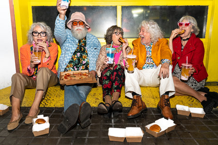 Group of happy senior friends with fancy clothing having party in the night on city streets - Cheerful elderly people wearing fashionable clothes celebrating and having fun outdoorsの写真素材