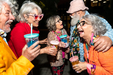 Group of happy senior friends with fancy clothing having party in the night on city streets -...