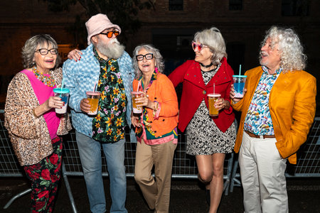 Group of happy senior friends with fancy clothing having party in the night on city streets -...