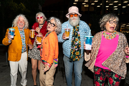 Group of happy senior friends with fancy clothing having party in the night on city streets - Cheerful elderly people wearing fashionable clothes celebrating and having fun outdoorsの写真素材