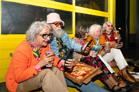 Group of happy senior friends with fancy clothing having party in the night on city streets - Cheerful elderly people wearing fashionable clothes celebrating and having fun outdoorsの写真素材