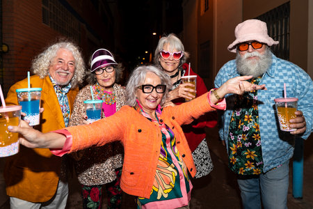 Group of happy senior friends with fancy clothing having party in the night on city streets - Cheerful elderly people wearing fashionable clothes celebrating and having fun outdoorsの写真素材