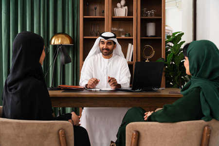 Emirati businessman is holding a meeting with two female clients in a modern office, discussing...