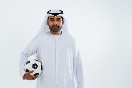 Middle-eastern doctor wearing emirati kandura working in the office - emirati businessman in traditional kandura holding a soccer ball.の写真素材