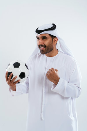 Middle-eastern doctor wearing emirati kandura working in the office - emirati man in traditional kandura celebrating success with a soccer ball after closing a dealの写真素材