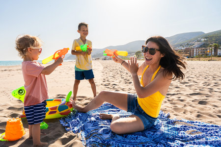 Happy beautiful asian family having fun at the beach during summertime vacation - Chinese mother and mixed race asian children spending time together at the sea, concepts about family, motherhood and diversityの写真素材