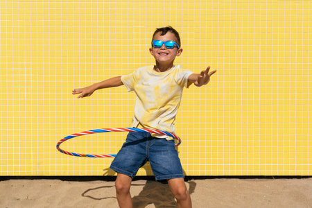 Happy and cool young boy having fun at the beach during summertime - Asian kid wearing sunglasses and swimwear portrait on a yellow background wallの写真素材