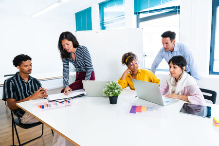 Multi-ethnic business team collaborating on a project, analyzing charts and data displayed on laptop...