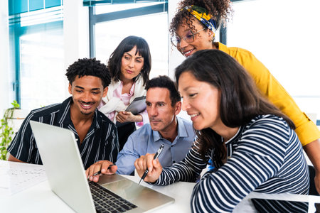 Diverse team of professionals gathered around a laptop, actively discussing and collaborating on a...