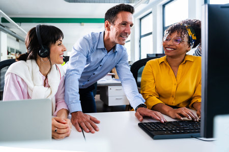 Business colleagues are working together on a computer in a modern office, collaborating on a...